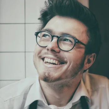 A young man with glasses posing for a photo for a review of Cana Korean Restaurant