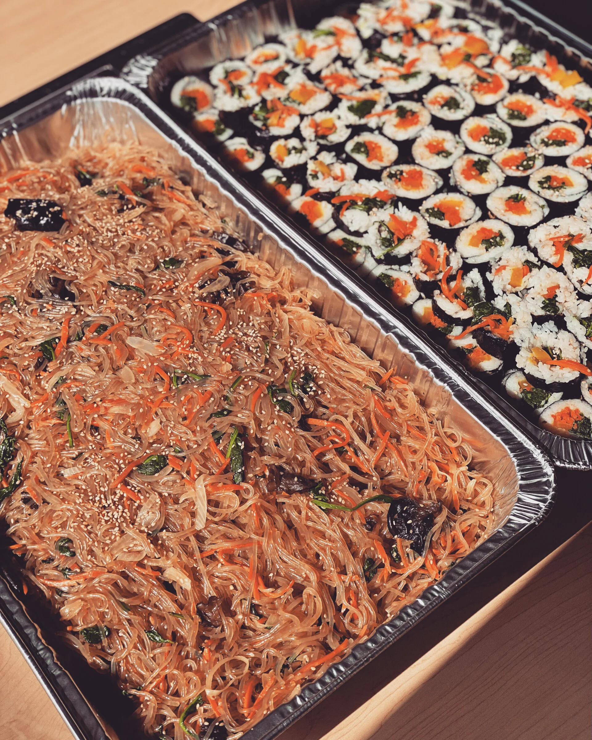 A large catering tray of japchae and kimbap from Cana Korean Restaurant